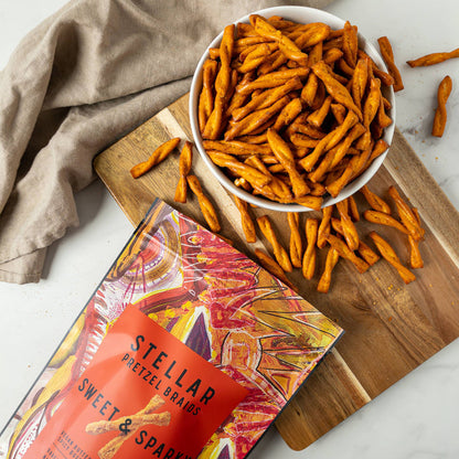 Stellar Sweet & Sparkle pretzel snack on a wooden board with packaging and scattered snacks.