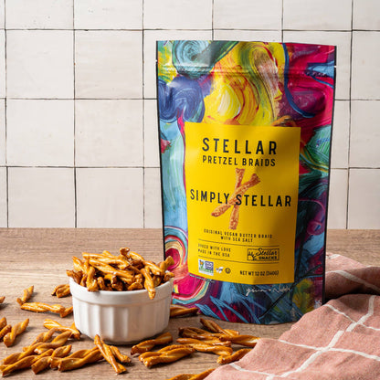 Colorful bag of Simply Stellar pretzel brands on a wooden surface with pretzels around.